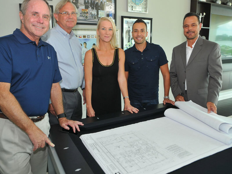 Town Home Developers. 4 males and one female developer standing around a table smiling at the camera.